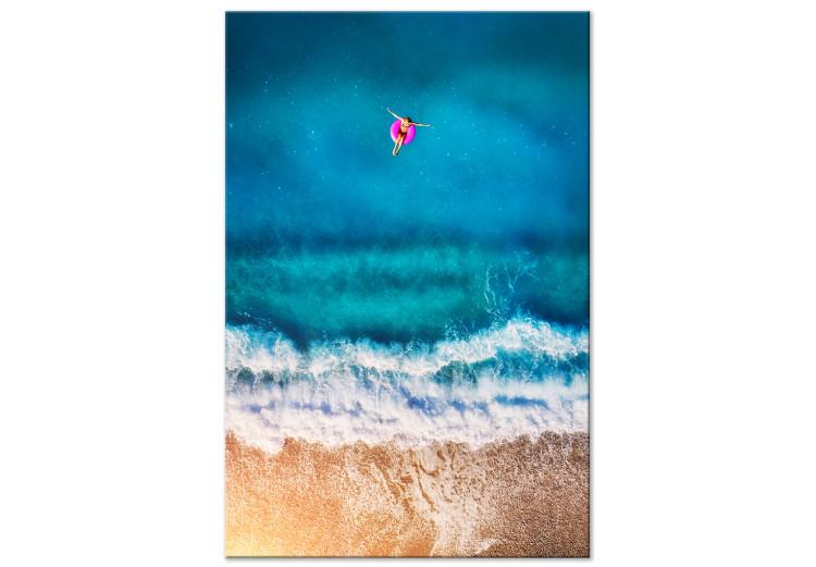 Canvas Print A moment of break - a figure sails to the sea on an inflatable wheel