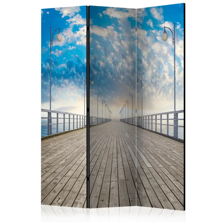 Pier - water under a long wooden bridge against the sky and clouds