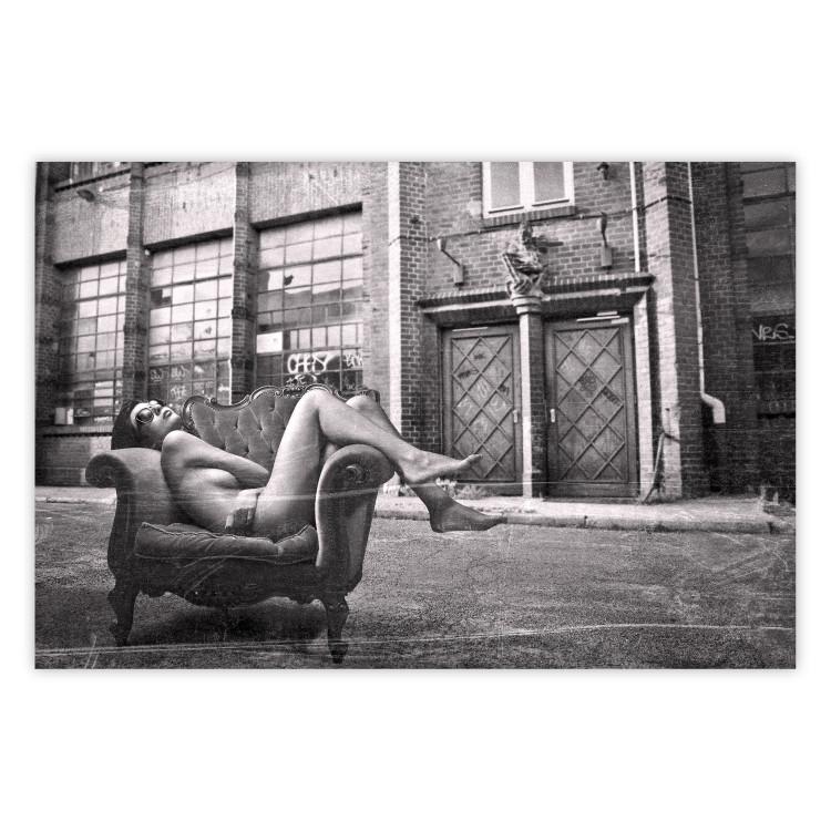 Poster Casual Pose - black and white landscape of a woman in a chair with a building in the background