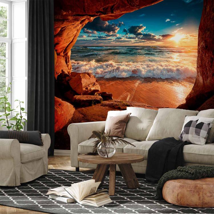Wall Mural Cave by the beach - landscape with a restless sea at sunset