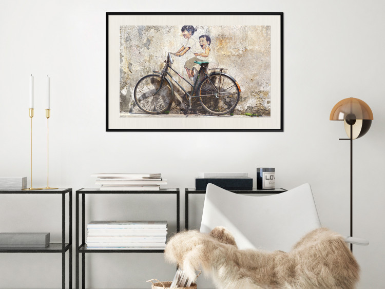 Wall Poster Carefree - retro black bicycle against a wall painted with children 130457 additionalImage 24